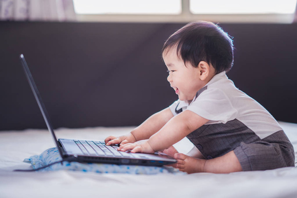 asiatisches Baby in Business-Suite sitzt und spielt Computer-Notebook - Foto, Bild