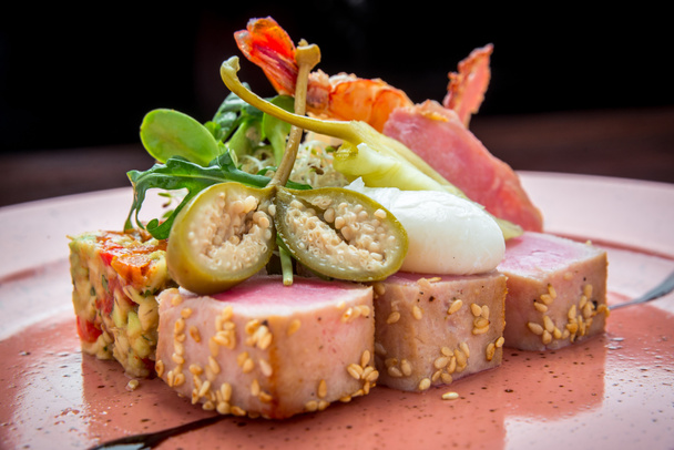 красивая еда: стейк с тунцом в кунжуте, лайм и свежий салат крупным планом на тарелке
 - Фото, изображение