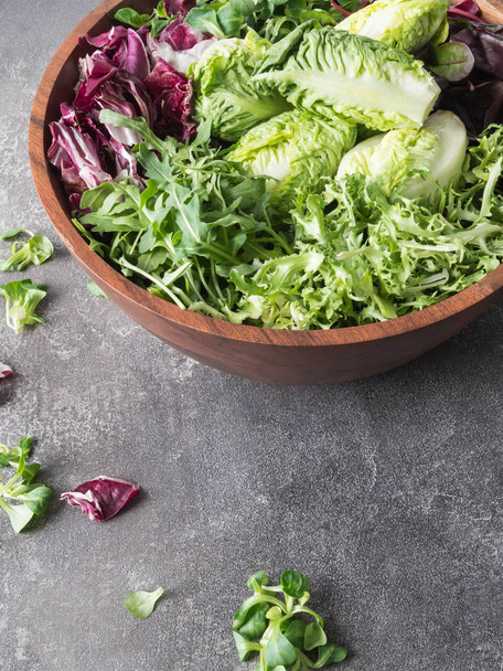 Various types of salad leaves in big wood bowl on a grey background - Foto, immagini