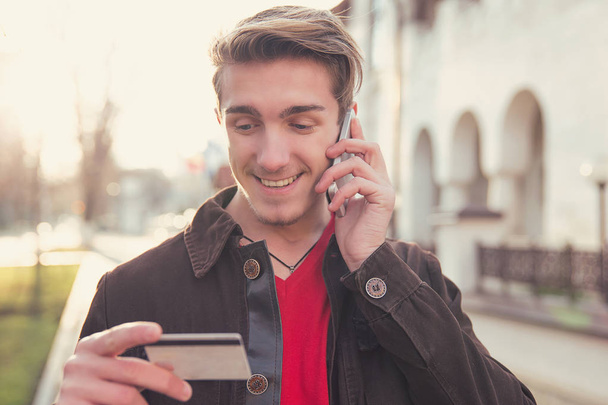Smiling man with card talking on phone - Foto, Imagem
