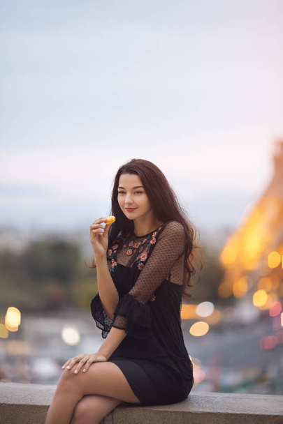 Mujer de París sonriendo comiendo la pastelería francesa macaron en París contra la torre Eiffel. - Foto, Imagen