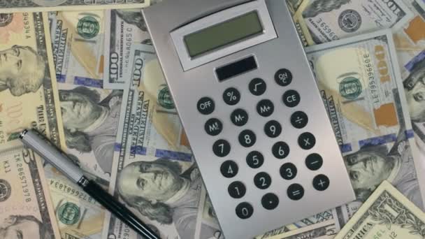 Rotation of the calculator and pen lying on the dollars. - Video, Çekim
