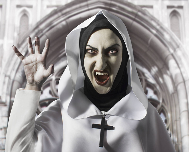 Pelottava paha nunna, jolla on torahampaat ja risti kaulassa huutaen. Halloween käsite, musta magia
. - Valokuva, kuva