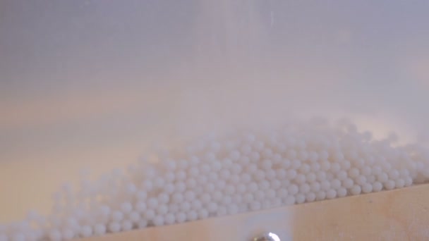 Tiimalasi pieniä valkoisia palloja
 - Materiaali, video