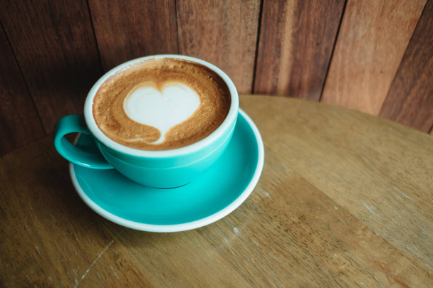 φλιτζάνι με καφέ έχει σχήμα καρδιάς στην κορυφή τοποθετημένο στο ξύλινο τραπέζι  - Φωτογραφία, εικόνα