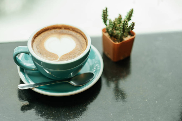Ansicht von oben. Tasse mit Kaffee hat eine Herzform auf der Oberseite und Kaktus pl - Foto, Bild