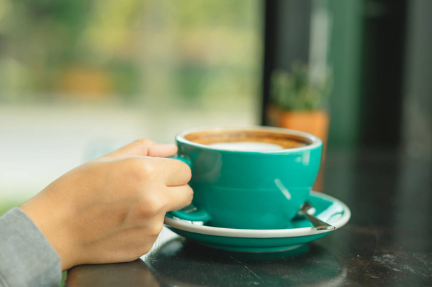 рука ділової жінки тримає чашку з кавою, поміщеною на дерев'яній
 - Фото, зображення