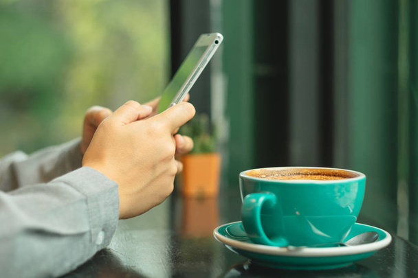 рука ділової жінки грає на смартфоні. на столі є чашка кофе
 - Фото, зображення