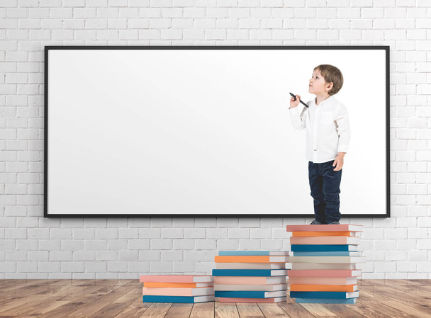 Little boy with a marker on books pile whiteboard - Foto, Imagen