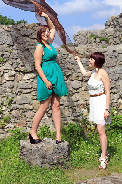 Две молодые женщины в мини-платьях веселятся с шарфом
 - Фото, изображение