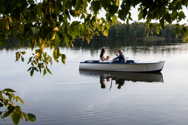 loving wedding couple in a boat on the lake - Фото, изображение