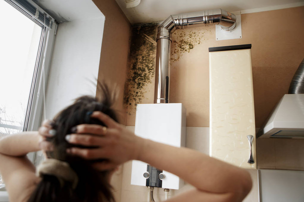 Primer plano de una mujer conmocionada mirando el molde en la pared
 - Foto, Imagen