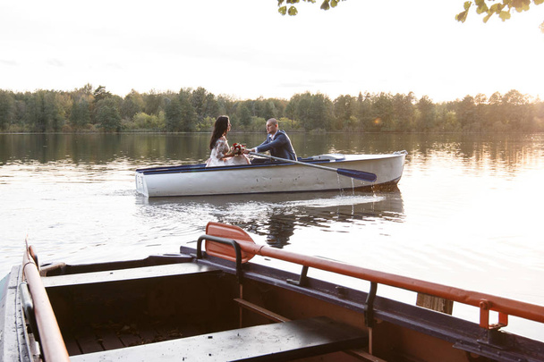 loving wedding couple in a boat on the lake - Foto, afbeelding