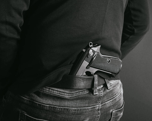 Gangster ukrywając jego pistolet za jego plecami. tyłu i białe zdjęcie - Zdjęcie, obraz
