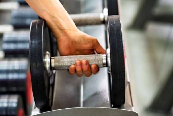 Hand grabs dumbbell in modern gym - Photo, Image
