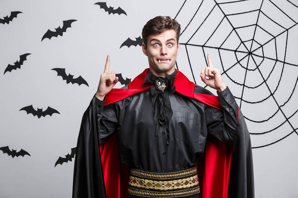 Vampire Halloween Concept - Portrait of handsome caucasian in Vampire halloween costume pointing on side
.  - Фото, изображение