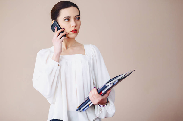 Επιχειρήσεων γυναίκα μιλάει στο τηλέφωνο με έγγραφα στα χέρια της - Φωτογραφία, εικόνα