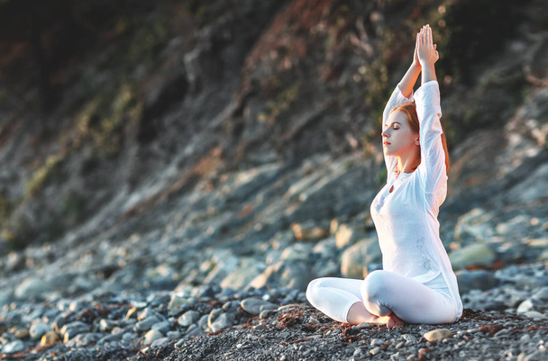 kadın yoga uygulamaları ve gün batımı b lotus pozisyonda derin derin düşünür - Fotoğraf, Görsel