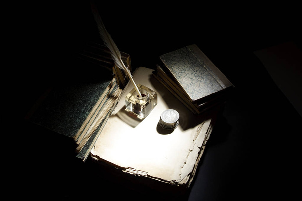 Vintage concept. Old fountain pen, papers and inkwell and silver coins on a black background - Foto, Imagen