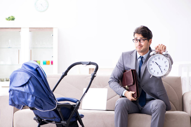 Businessman looking after newborn baby at home and teleworking - Photo, Image