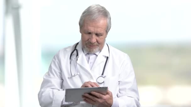 Ηλικιωμένος γιατρός πληκτρολογώντας στον υπολογιστή tablet. - Πλάνα, βίντεο