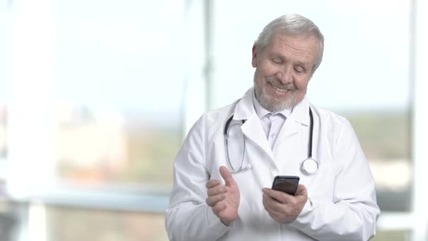 Médico sonriente usando su teléfono inteligente
. - Imágenes, Vídeo
