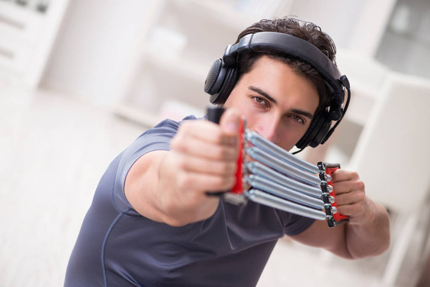 Hombre haciendo deportes con banda de resistencia y escuchando música - Foto, Imagen