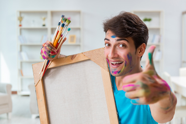 Młody zabawny artysta pracujący nad nowym malarstwem w swoim studio - Zdjęcie, obraz