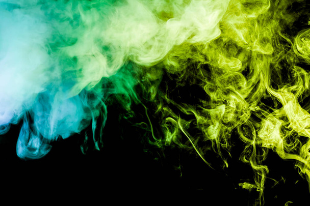 Fumée dense multicolore de couleurs vertes et bleues sur un fond isolé noir. Contexte de la fumée vape
 - Photo, image