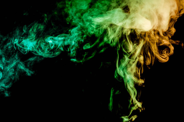 Παχύ κίτρινο και πράσινο πολύχρωμο καπνού από πάνω σε μαύρο φόντο απομονωμένες. Φόντο από τον καπνό του vape - Φωτογραφία, εικόνα
