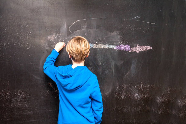 Küçük bir çocuk bir şey bir kara tahta üzerinde boyama arkadan görünüm - Fotoğraf, Görsel