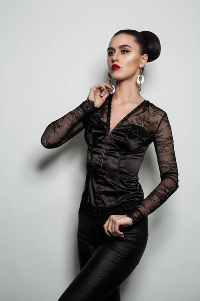 Mulher modelo de moda em roupas pretas em pé contra a parede cinza
  - Foto, Imagem