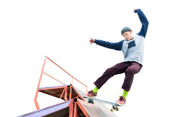 Teen skater in a hoodie sweatshirt and jeans slides over a ramp on a skateboard isolated on white - Foto, afbeelding