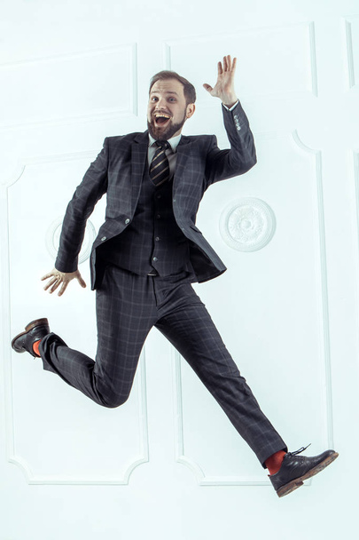 Funny cheerful businessman jumping in air over white background - Photo, Image