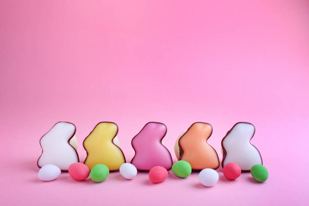 Colorful glazed cookies shaped rabbits with candies on pink background - Foto, afbeelding