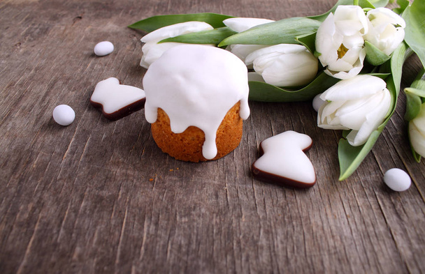 Composizione pasquale con tulipani bianchi freschi, torta pasquale e biscotti smaltati a forma di coniglio su fondo di legno
 - Foto, immagini