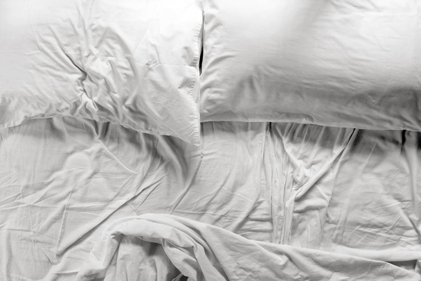 Незроблене ліжко в спальні з двома подушками і оббитим простирадлом
 - Фото, зображення