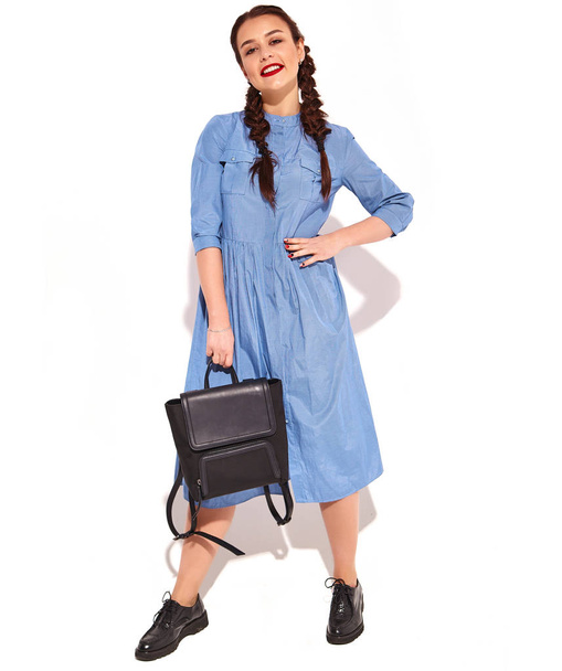 Portrait of young happy smiling woman model with bright makeup and red lips with two horns in hands in summer colorful blue dress and back pack isolated on white. Full length - Φωτογραφία, εικόνα