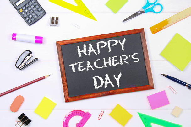 Tekst krijt op een schoolbord: Happy Teacher's Day. Schoolbenodigdheden, kantoor, boeken, appel. - Foto, afbeelding