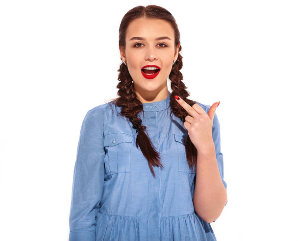 Portrait of young happy smiling woman model with bright makeup and red lips with two horns in hands in summer colorful blue dress and back pack isolated on white. Showing fuck off sign - Fotoğraf, Görsel
