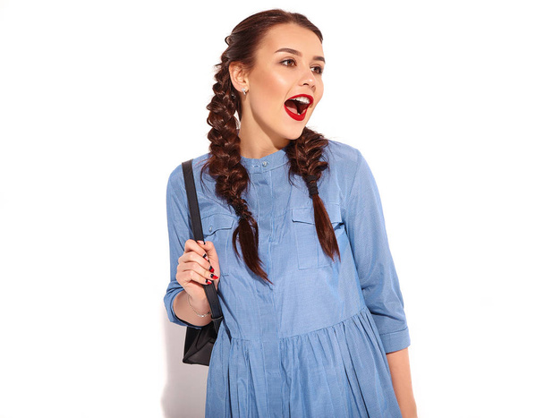 Muotokuva nuori onnellinen hymyilevä nainen malli kirkas meikki ja punaiset huulet kaksi sarvea käsissä kesällä värikäs sininen mekko ja reppu eristetty valkoinen
 - Valokuva, kuva