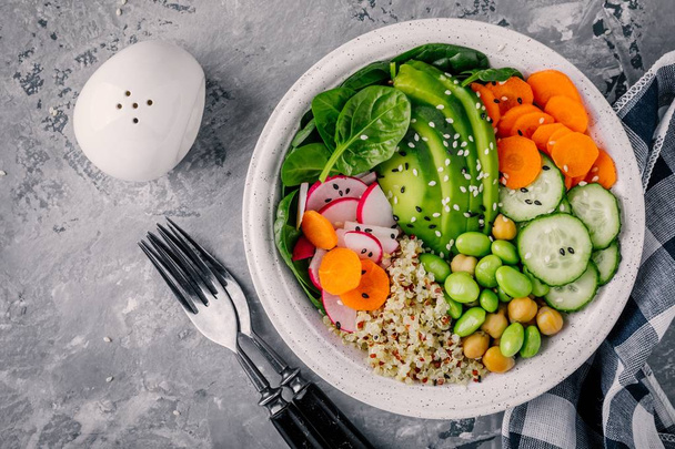 Vegan Buddha bowl salad with spinach, quinoa, roasted chickpeas, grilled chicken, avocado, edamame beans, cucumbers, sesame and pumpkin seeds.  - Photo, Image