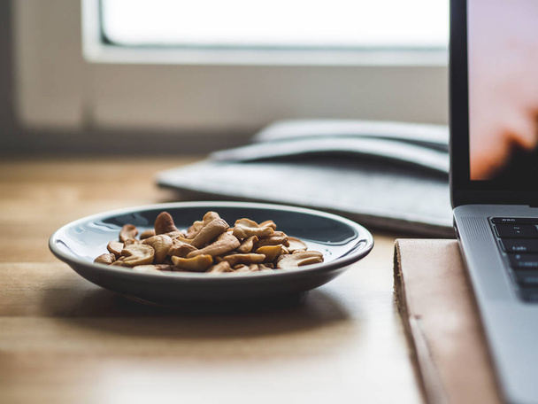 Some cashew nuts on small snack dish on work desk. - Zdjęcie, obraz