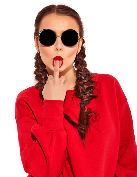 Portrait of young happy smiling woman model with bright makeup and colorful lips with two horns and sunglasses in summer red clothes isolated on white. Licking middle finger, fuck off sign - Foto, Imagen