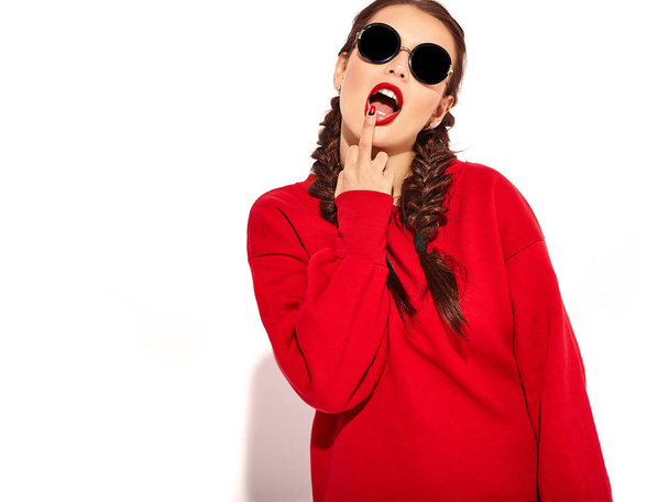 Portrait of young happy smiling woman model with bright makeup and colorful lips with two horns and sunglasses in summer red clothes isolated on white. Licking middle finger, fuck off sign - Φωτογραφία, εικόνα