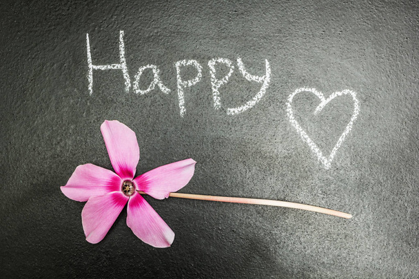 Flor rosa em um fundo preto, a palavra "feliz
" - Foto, Imagem