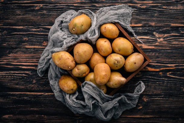 Raw potatoes. On a brown wooden background. Cooking. Free space for text. Top view. - Foto, Imagen