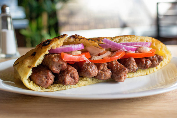 Вкусный сэндвич с кебабом из сербской говядины в пита-хлебе со свежими салатами
 - Фото, изображение