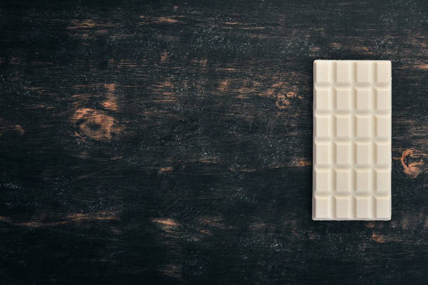 White milk chocolate on a wooden table. Top view. Copy space for text. - Fotó, kép