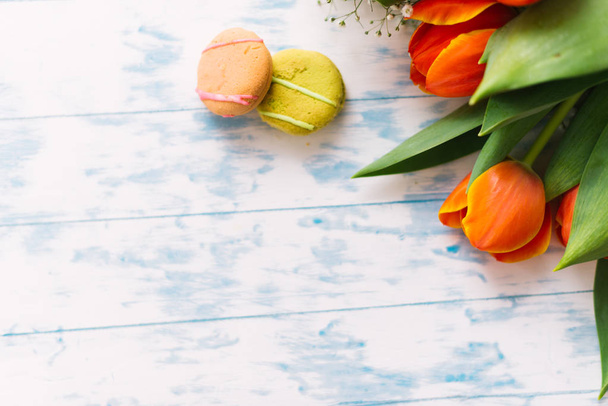 Blossoming tulips with macaroons on a light wooden background. Still life, spring concept - Fotó, kép